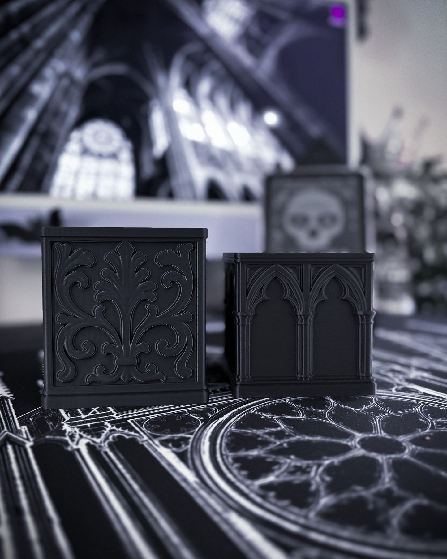 Black baroque desk organisers with gothic detailing on a table, cathedral interior in the background