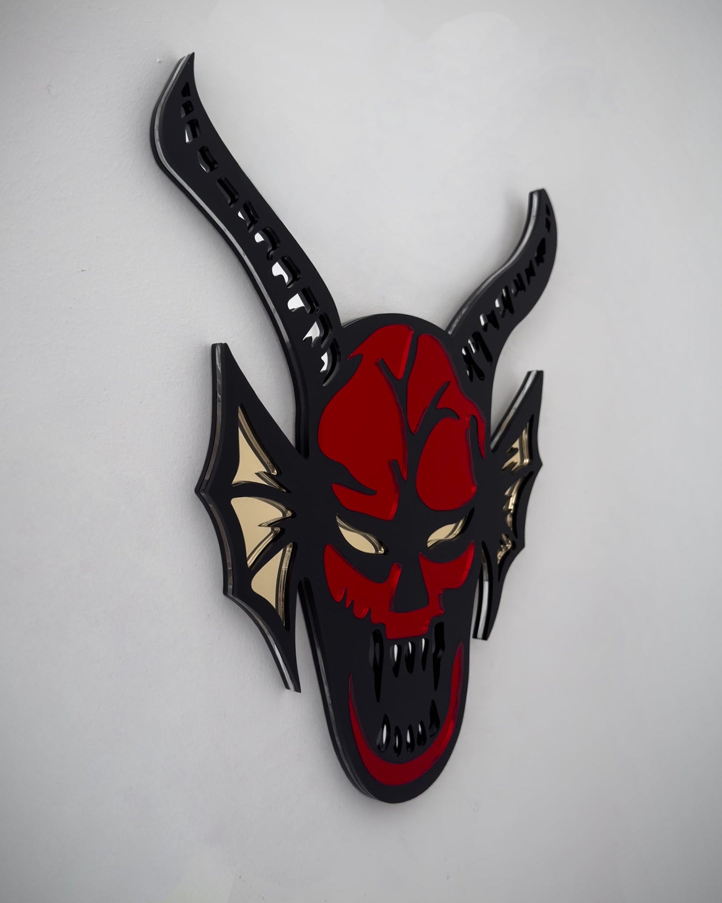 Side view of hellfire demon acrylic mirror wall art in red, black and yellow with horns and fangs