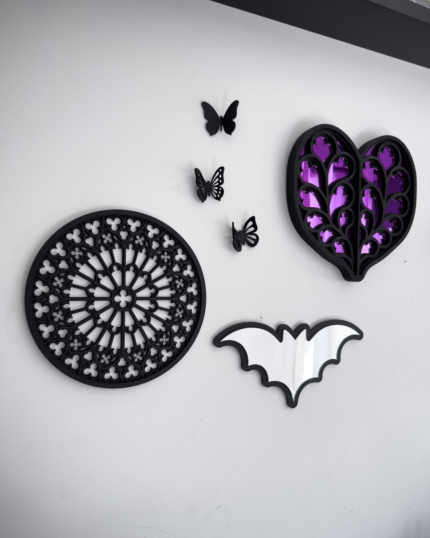 Side view of Gothic gallery wall with Notre Dame rose window tracery, bat mirror and purple heart or Yorkshire cathedral wall art on a white wall