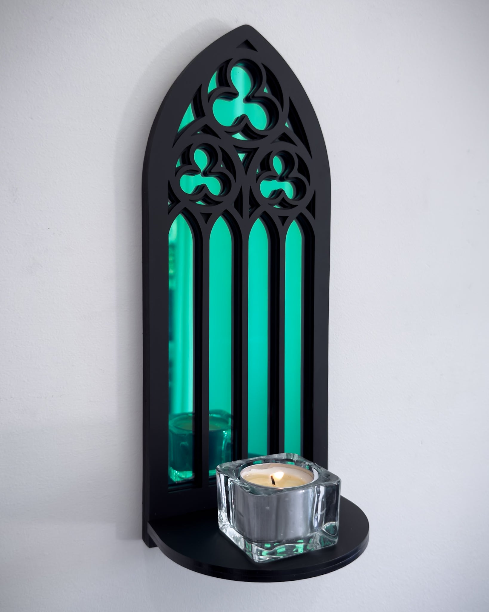 Close-up side view of gothic cathedral wall shelf in black layered acrylic with green acrylic mirror inset and candle display