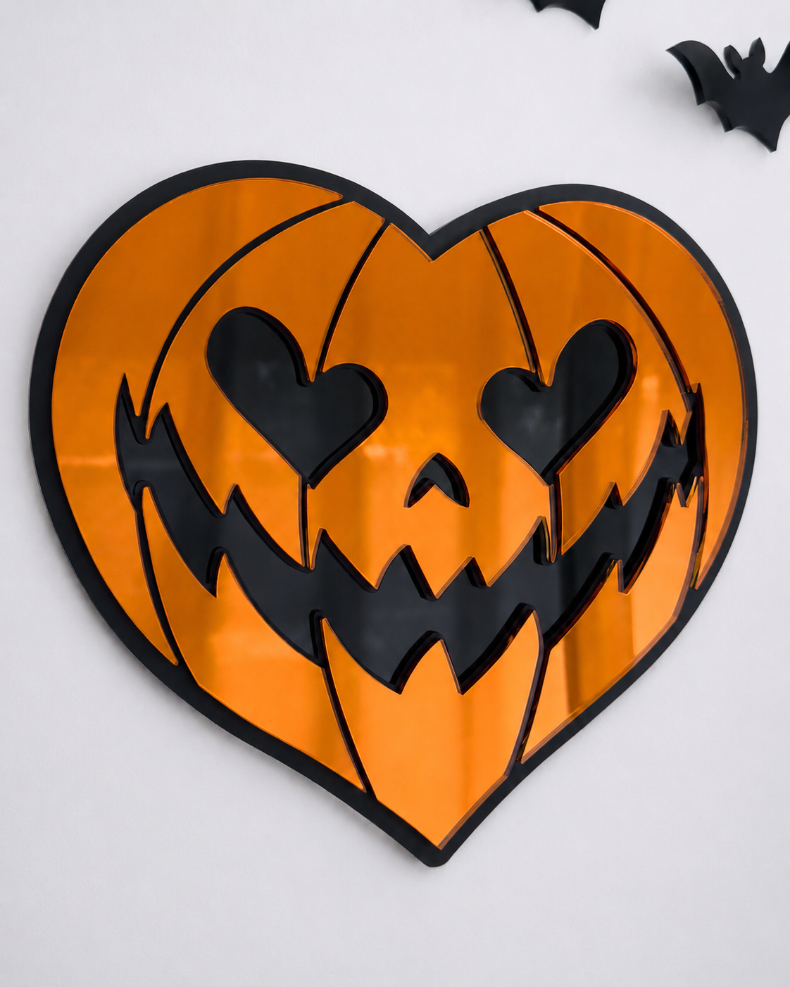 Orange heart-shaped pumpkin mirror wall art in layered black acrylic on a bright cool-toned wall