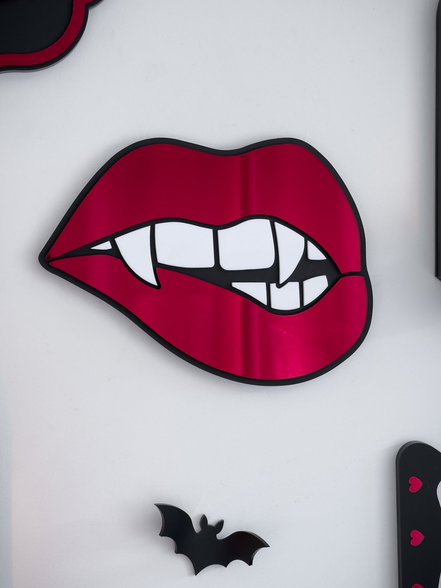 Vampire lips mirror in red acrylic with fangs on a white wall