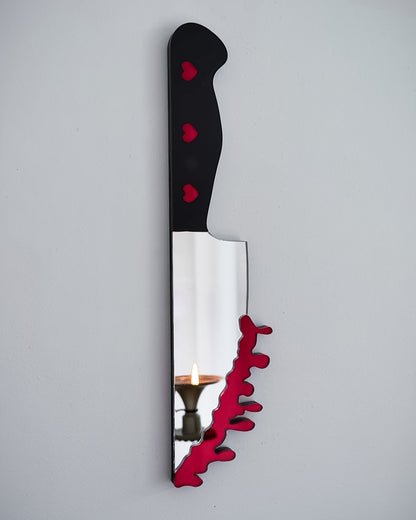 Bloody knife mirror wall art with heart handle and candle reflection on white wall