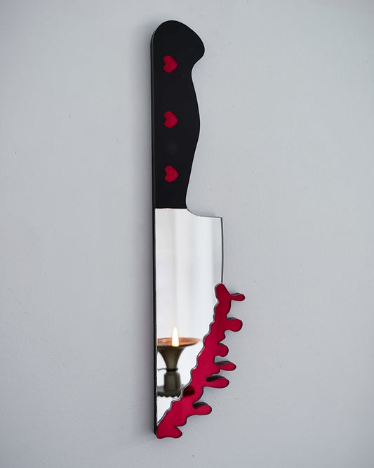Bloody knife mirror wall art with heart handle and candle reflection on white wall