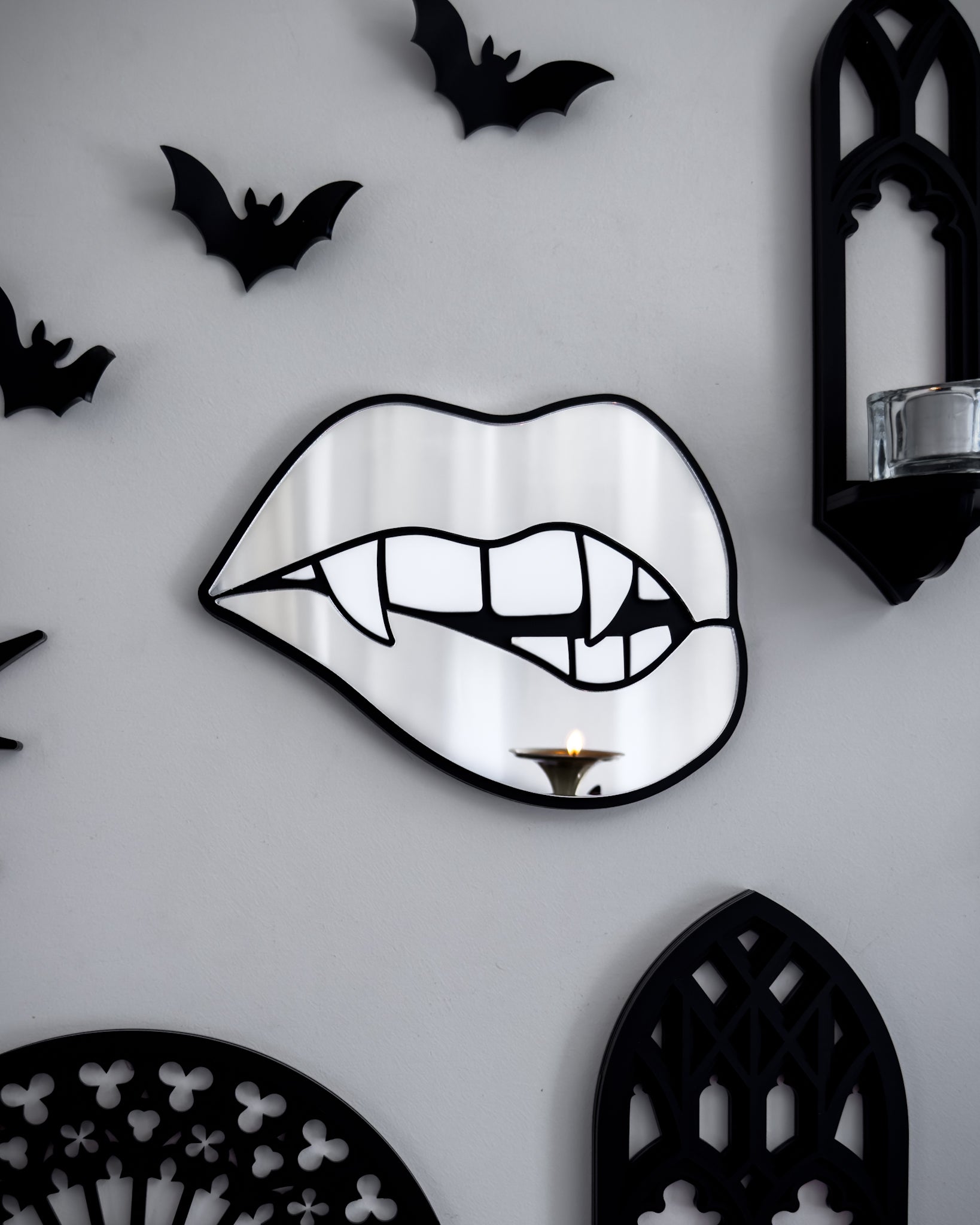 Silver mirror vampire lips wall art styled on a gothic gallery wall with black bats, cathedral shelf, and candlelight