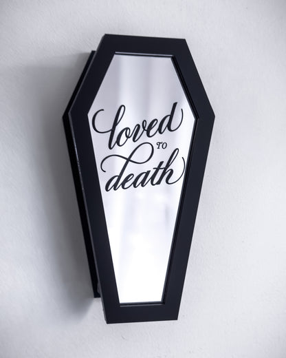 Black coffin-shaped wall propagation vase with engraved mirror front on white wall