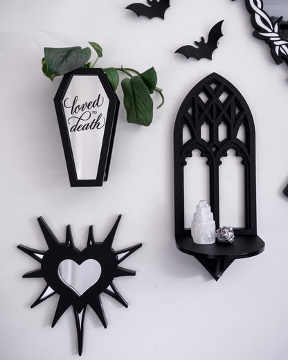 Black coffin wall propagation vase styled with gothic gallery wall decor on a white wall