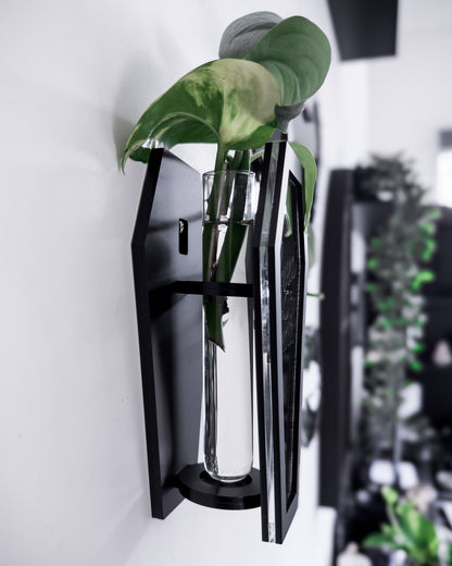 Side view of black coffin wall propagation vase holding a glass tube and plant cutting