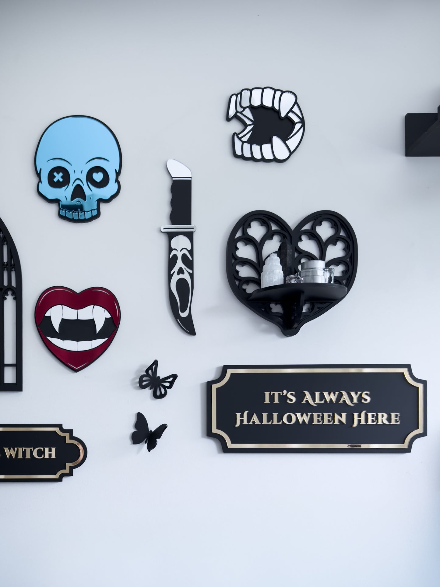 Gothic wall art gallery with skull, vampire lips, knife and Halloween plaque on white wall