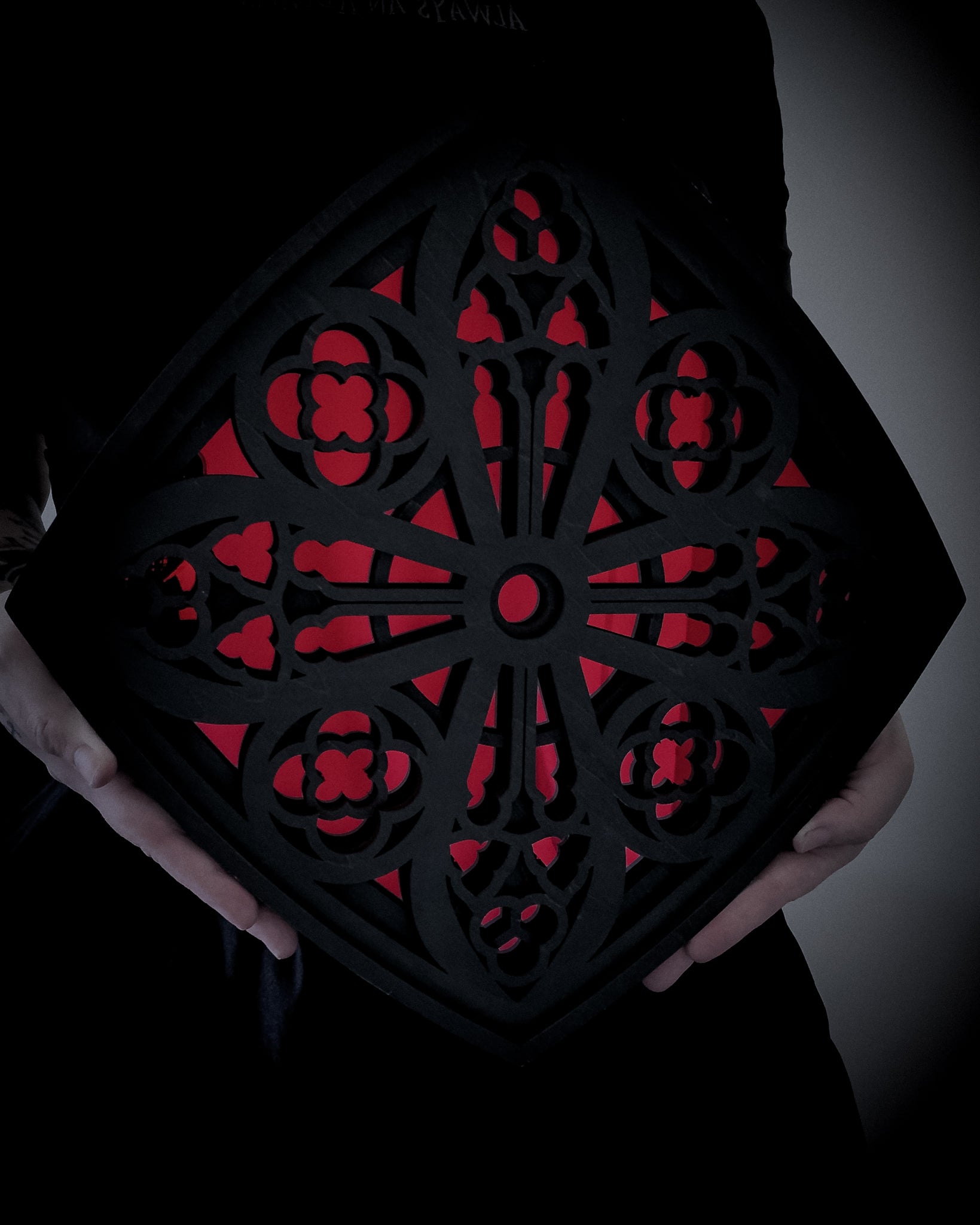 Cologne Cathedral Mirror in black layered wood with red acrylic mirror, shown held for scale