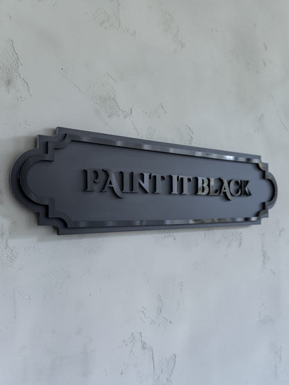Angled view of paint it black gothic wall art plaque on textured grey wall