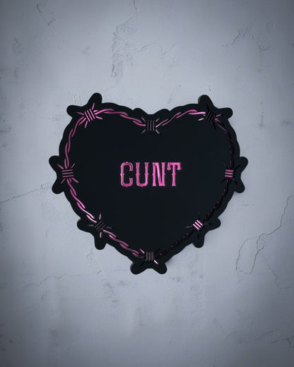 Cunt gothic heart wall art with barbed wire design in pink and black acrylic on textured grey wall