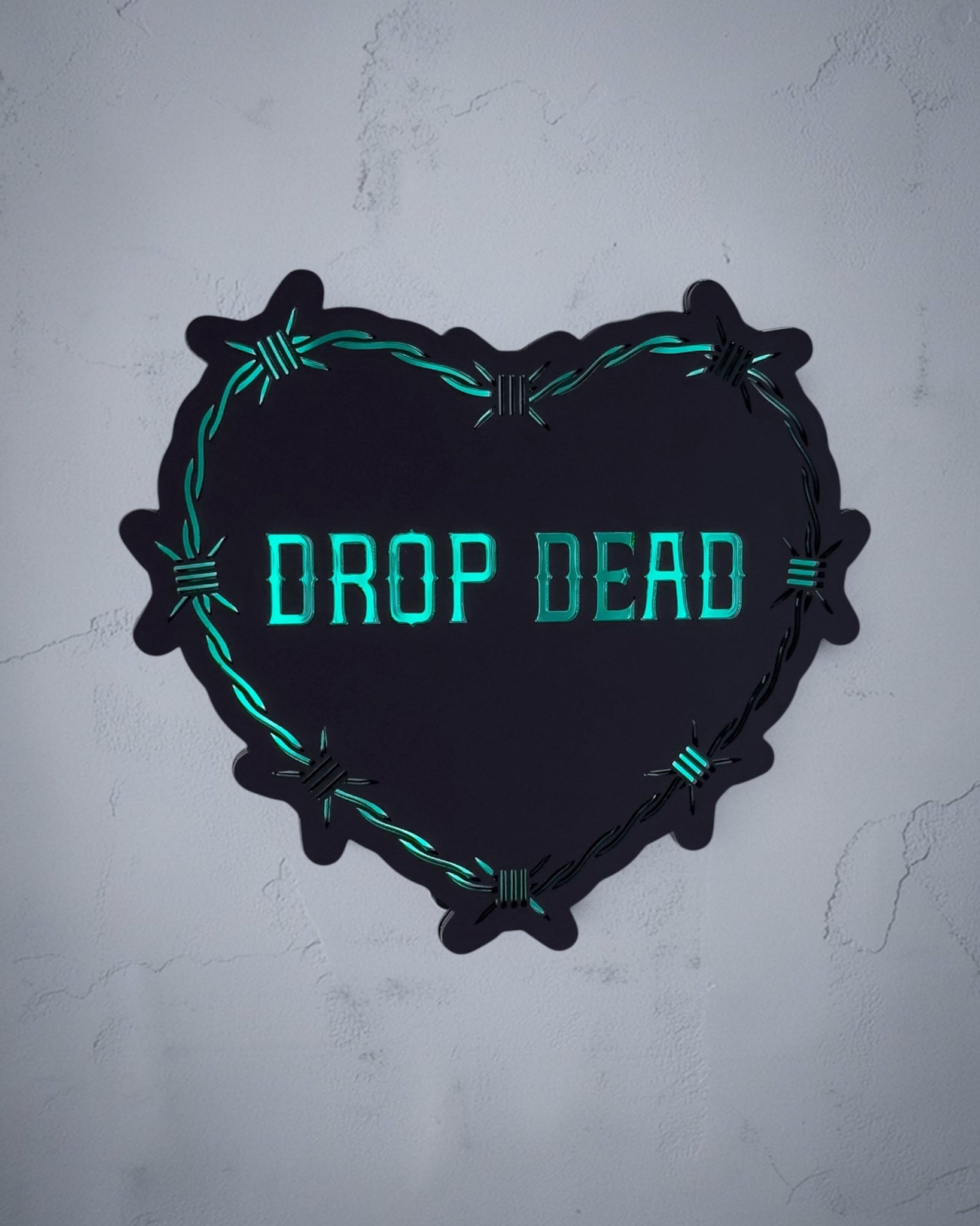 Drop Dead gothic heart wall art with barbed wire design in green and black acrylic on textured grey wall