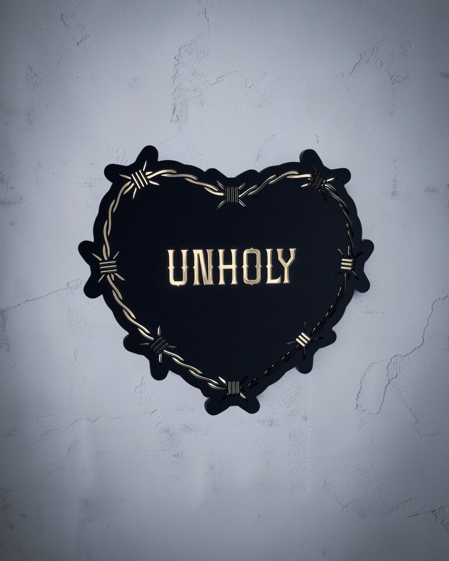Unholy gothic heart wall art with barbed wire design in gold and black acrylic on textured grey wall