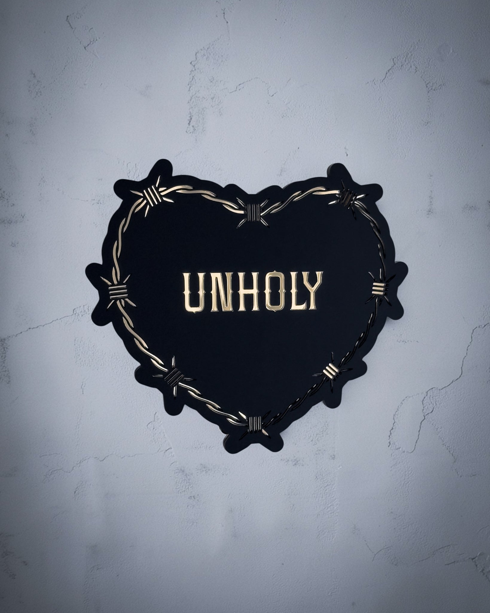 Unholy gothic heart wall art with barbed wire design in gold and black acrylic on textured grey wall