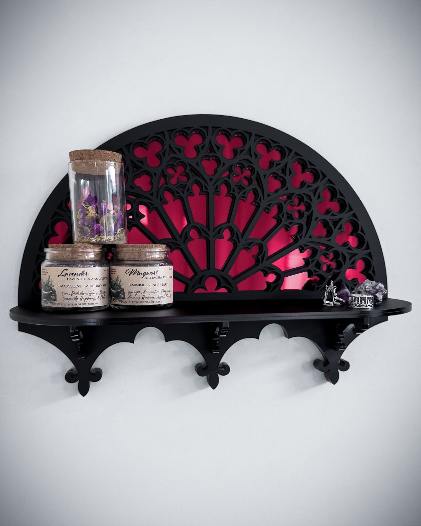 Black gothic cathedral wall shelf with mirror centre styled with jars and crystals