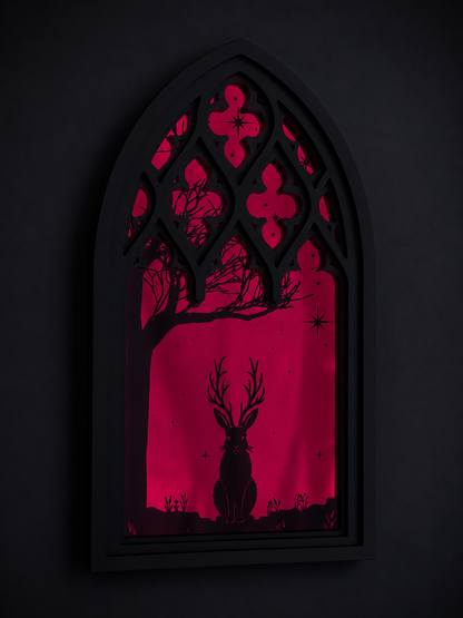 Gothic-style Cathedral window with red silhouette of a Jackalope and tree against a dark mirror background