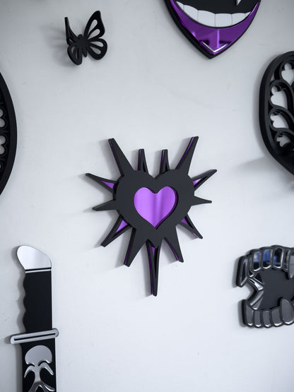 Close-up of gothic gallery wall featuring purple barbed heart wall art  mirror with knife decor and butterfly accents