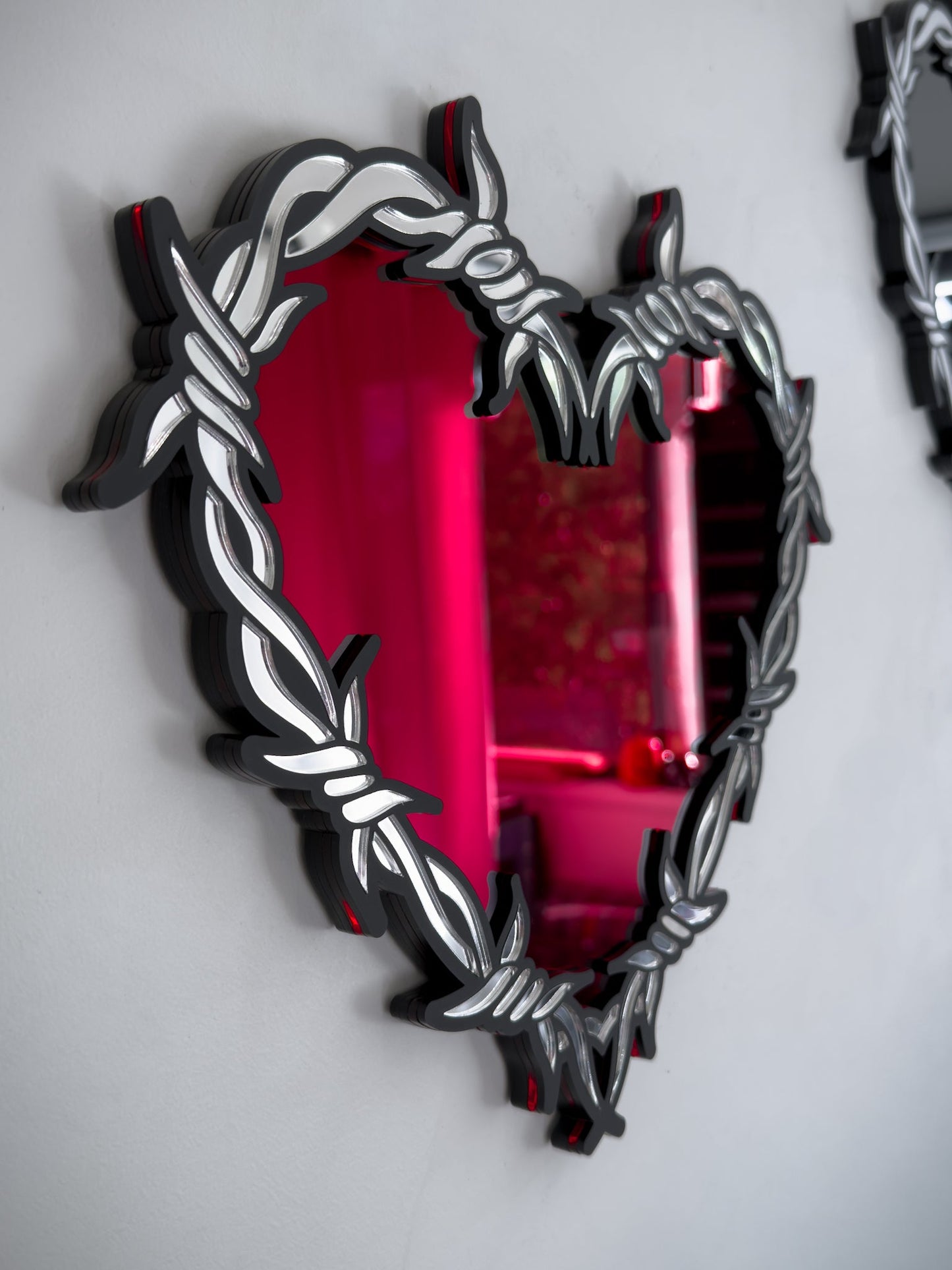 Side view of silver and red barbed wire heart mirror in layered acrylic gothic wall decor