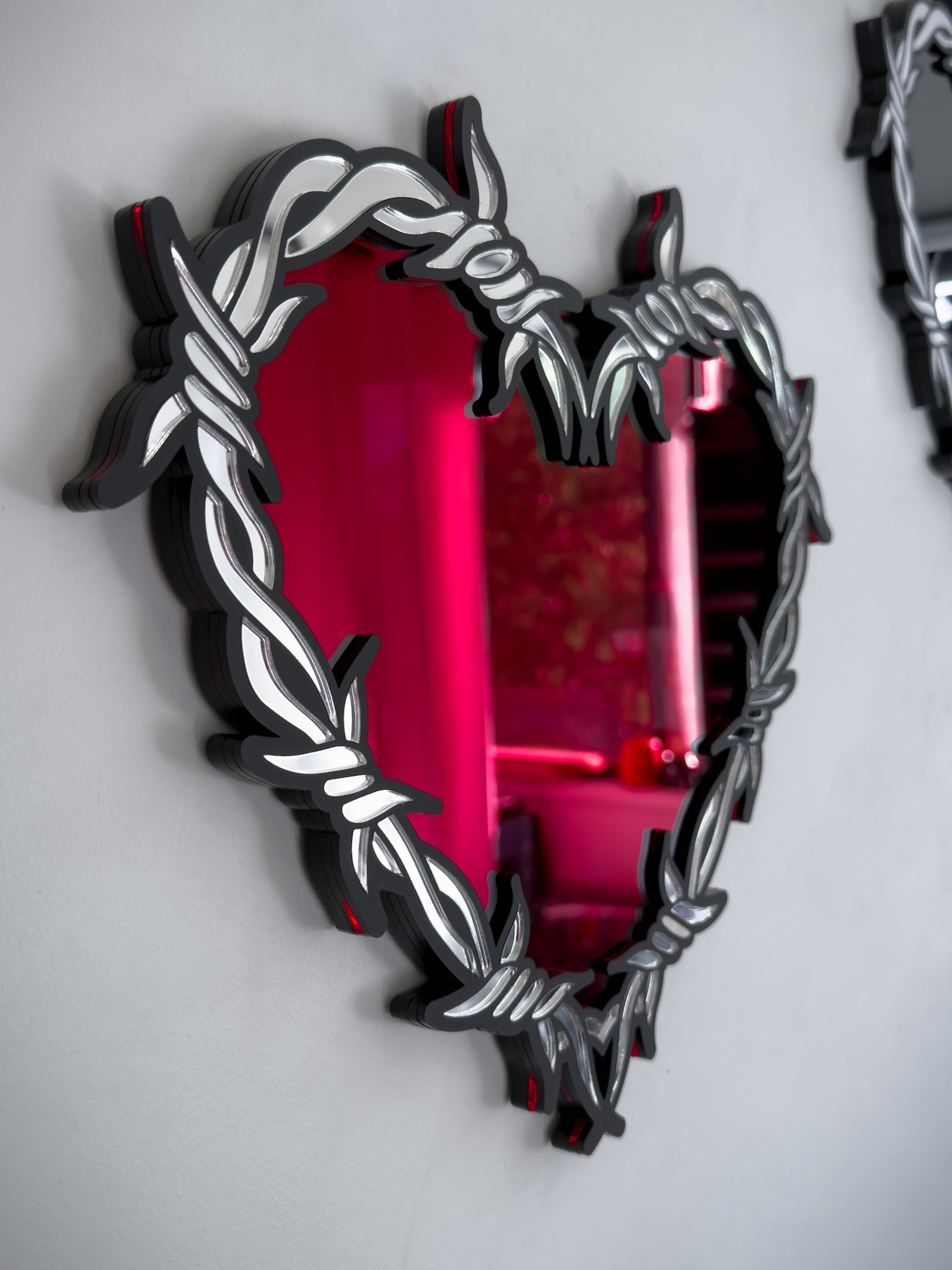 Side view of silver and red barbed wire heart mirror in layered acrylic gothic wall decor