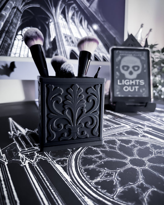 Black baroque organiser with gothic detailing holding makeup brushes, cathedral interior in background