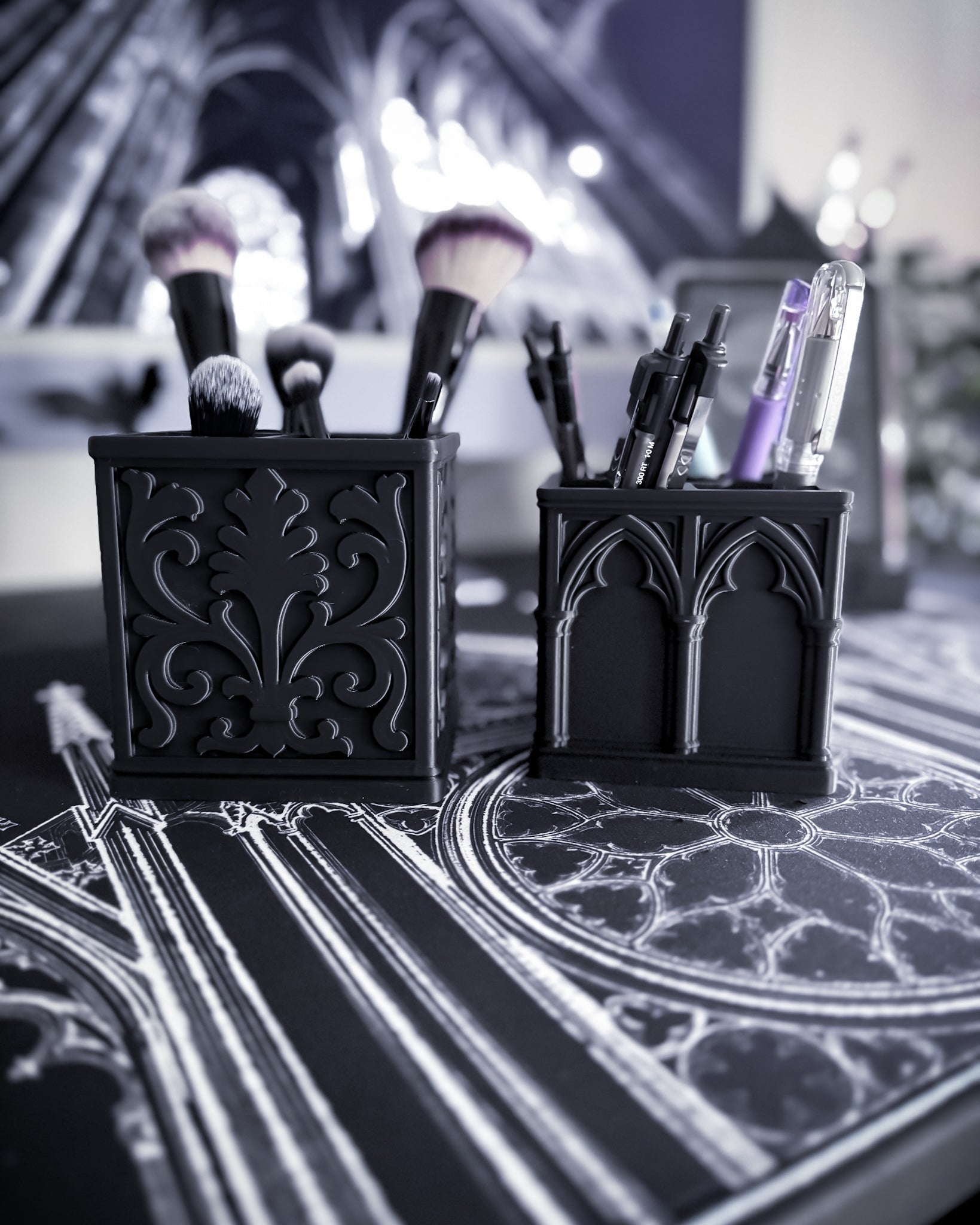Black baroque organisers with gothic detailing holding makeup brushes and pens with a cathedral interior in background