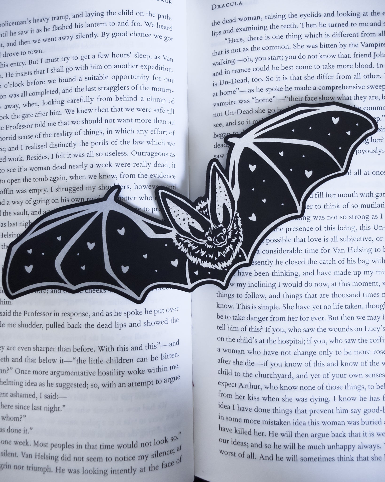 Gothic bat bookmark in black and silver leatherette with heart detail, resting on an open book