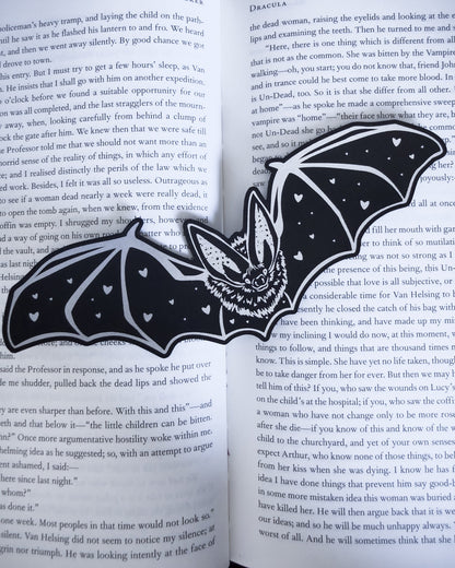 Gothic bat bookmark in black and silver leatherette with heart detail, resting on an open book