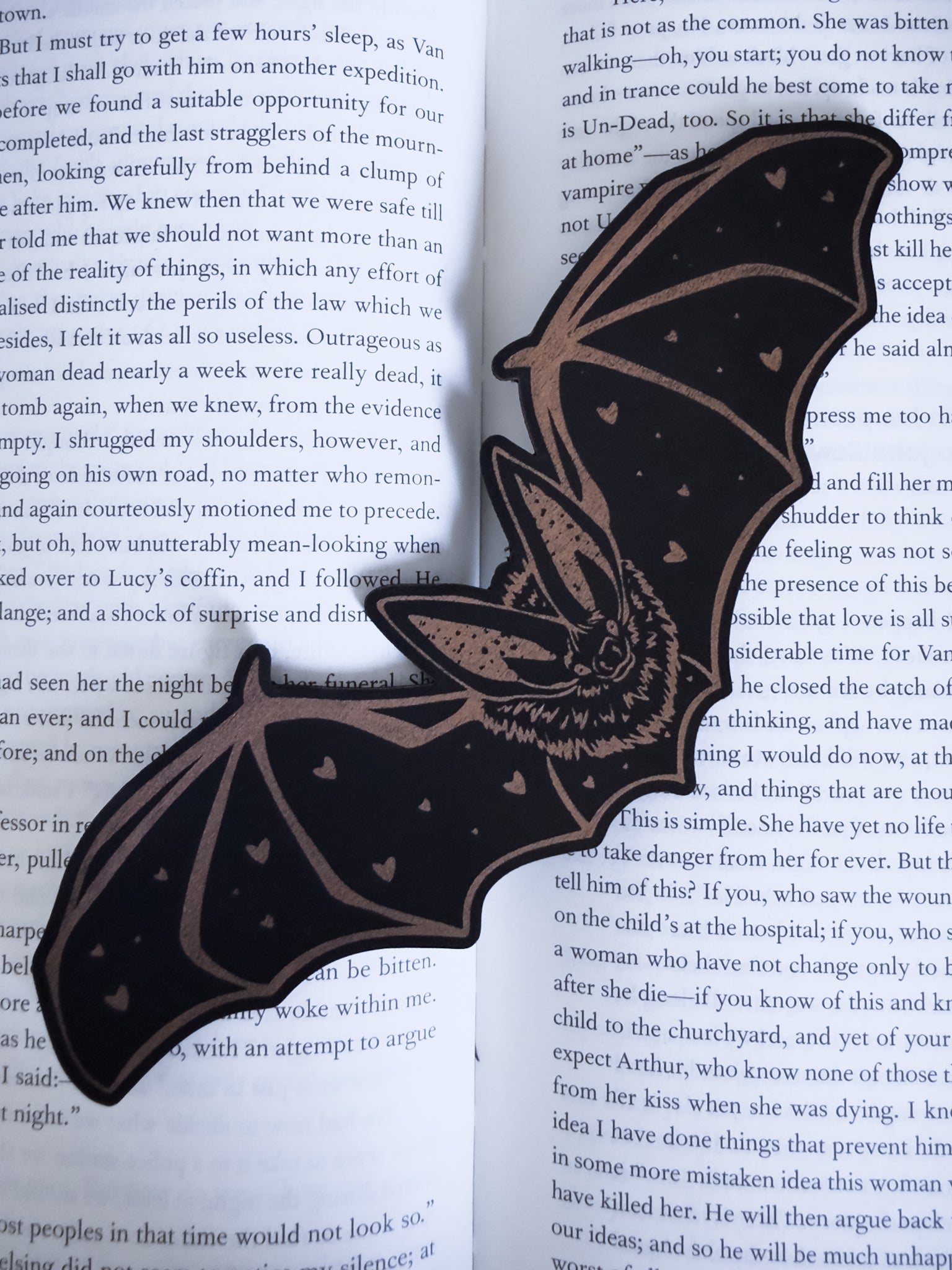 Gothic bat bookmark in black and copper leatherette with heart detail, resting on an open book