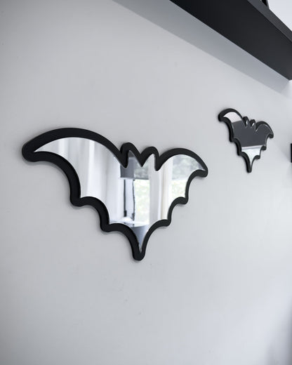 Side view of Silver bat mirror wall art with black frame on a white wall