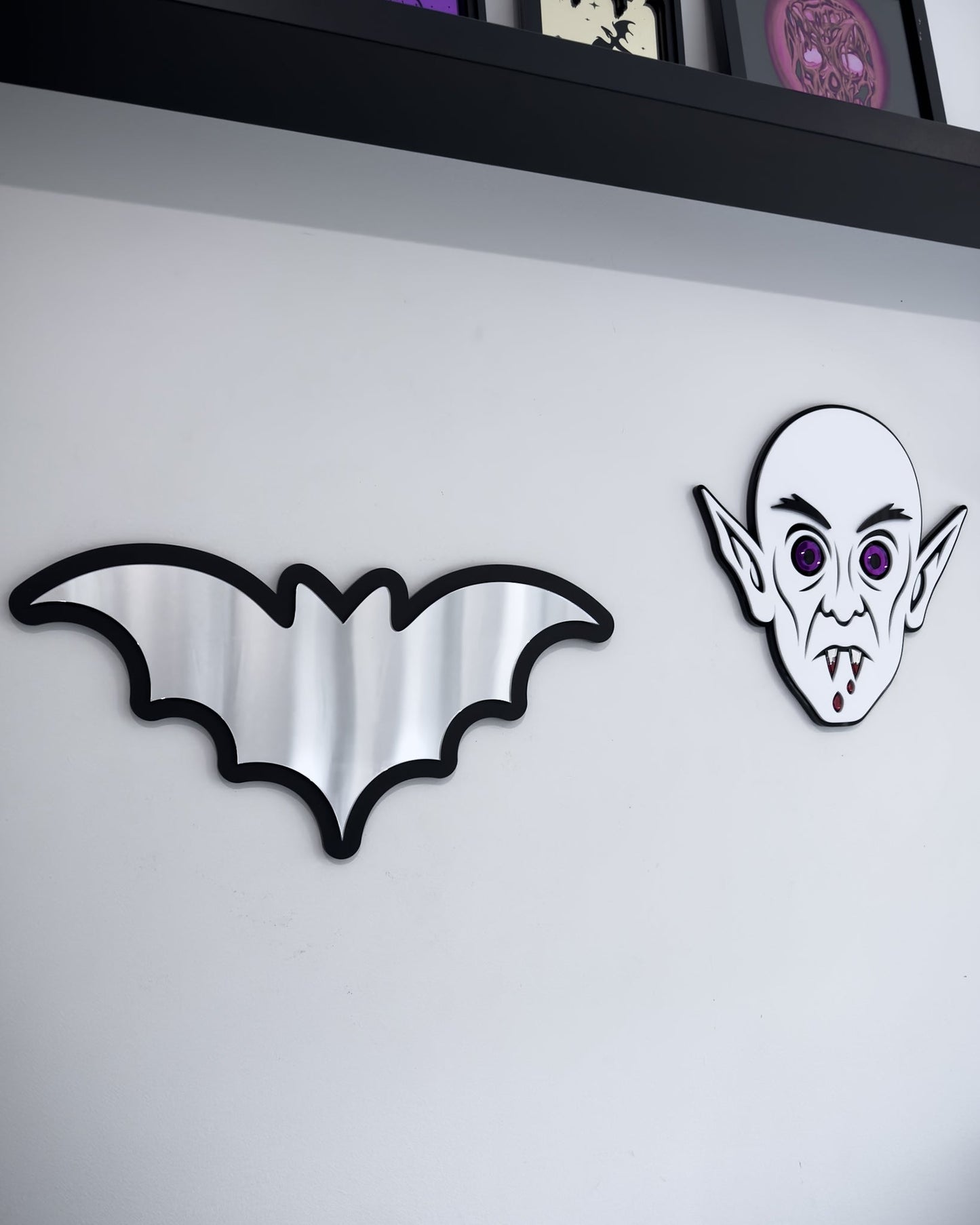 Bat mirror wall art in a gothic wall display with Nosferatu face decor on a white wall