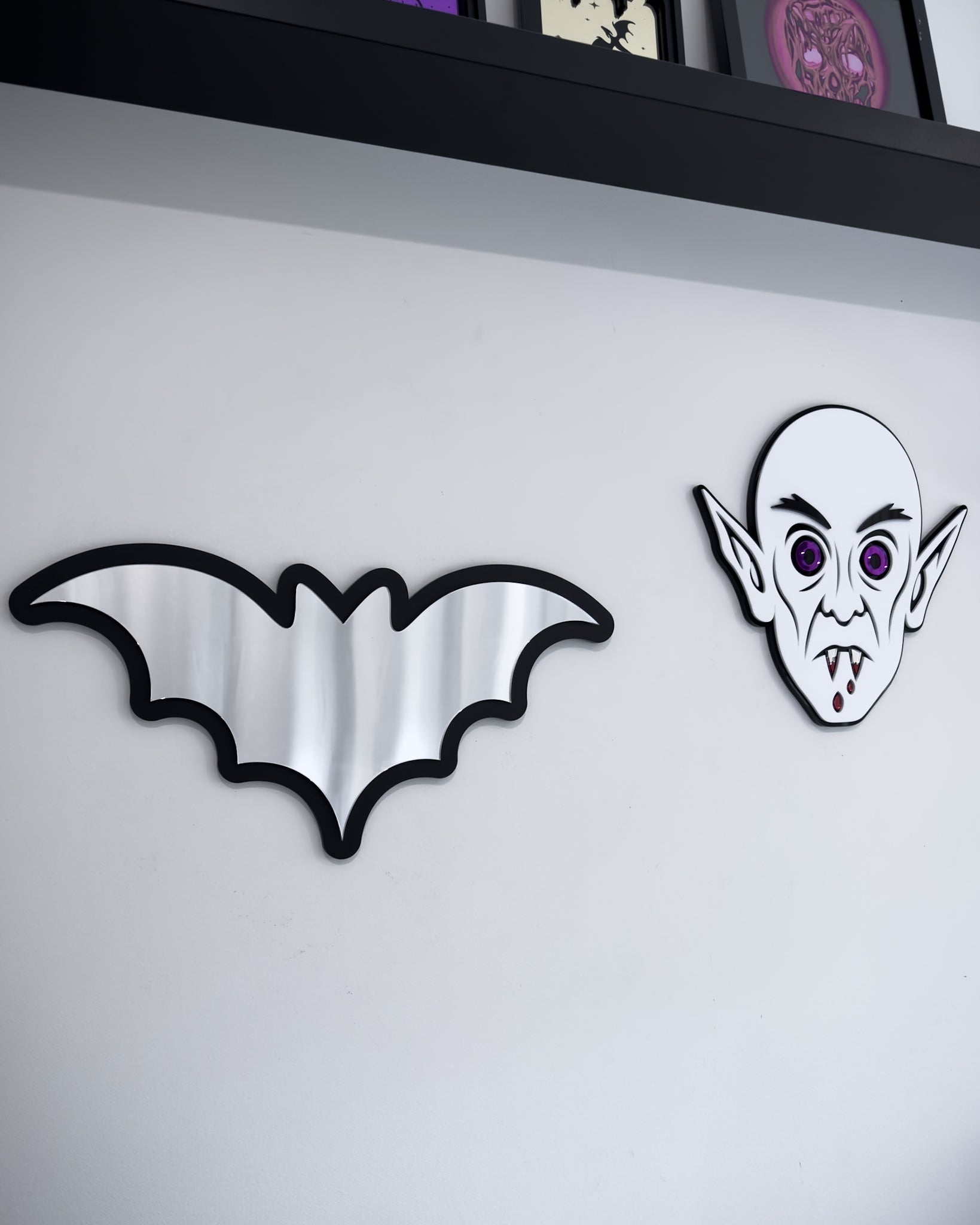 Bat mirror wall art in a gothic wall display with Nosferatu face decor on a white wall
