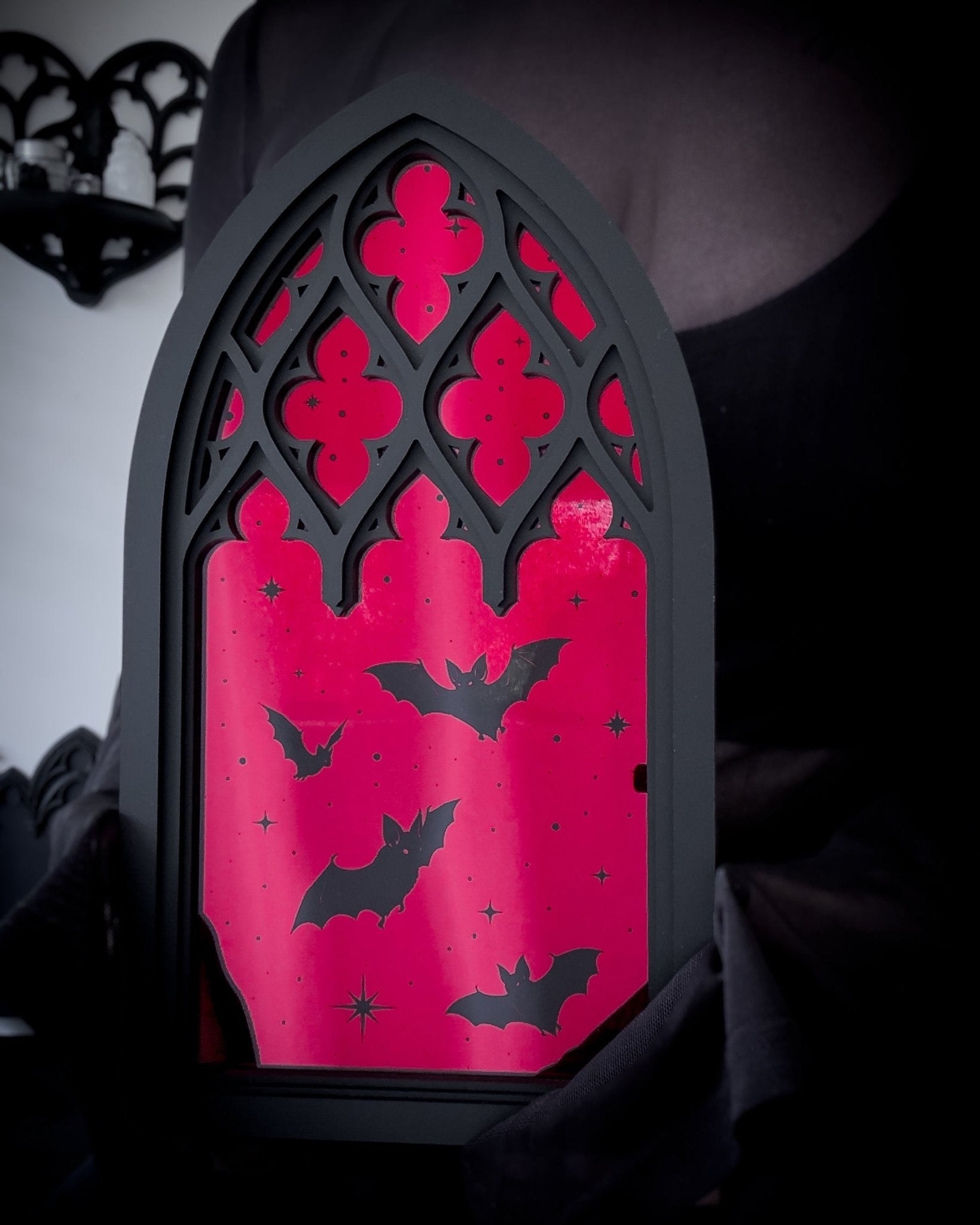 Gothic cathedral window mirror with red acrylic and bat silhouettes, held for scale
