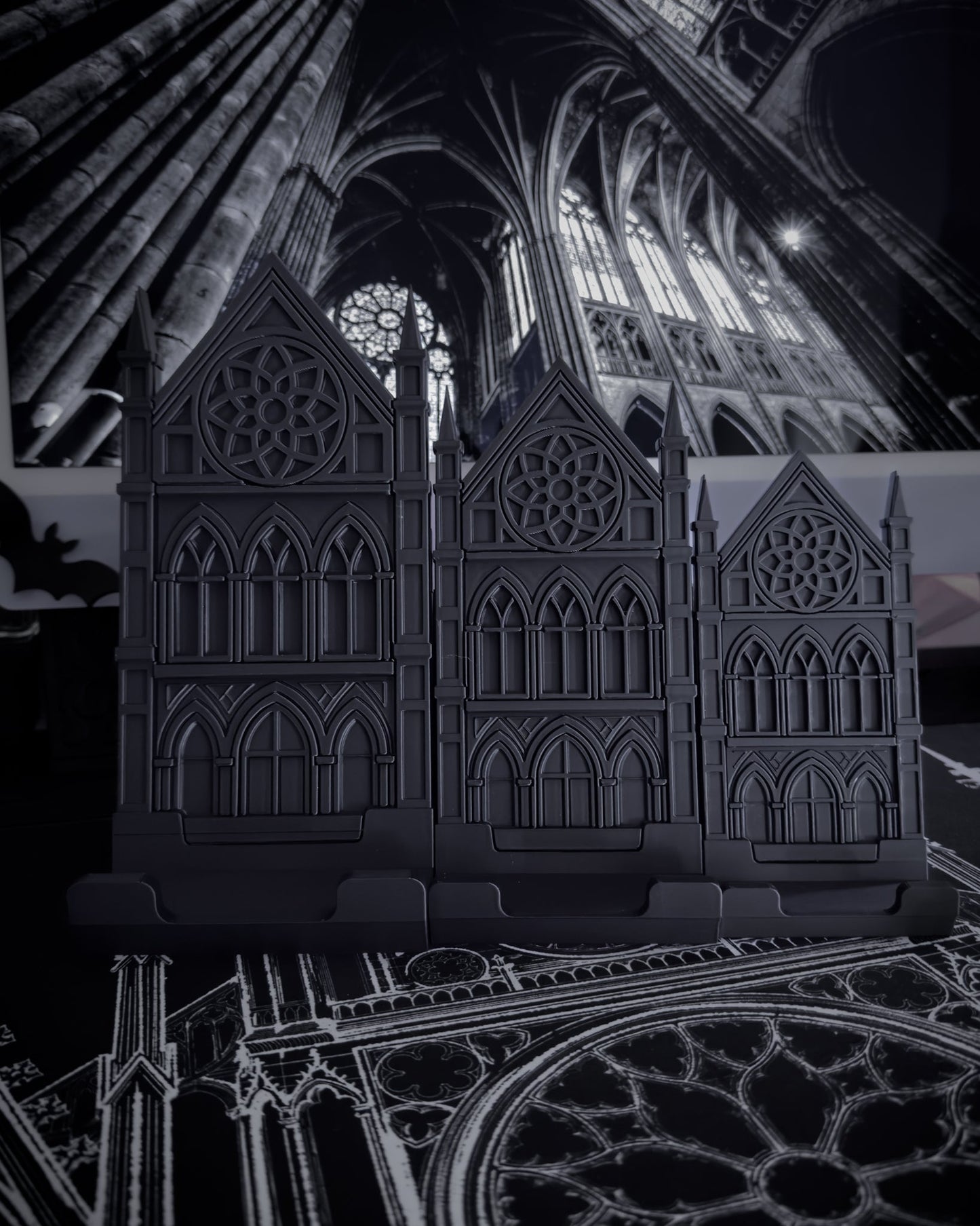Large, medium, small Black gothic cathedral device stands on a table with cathedral interior imagery in the background