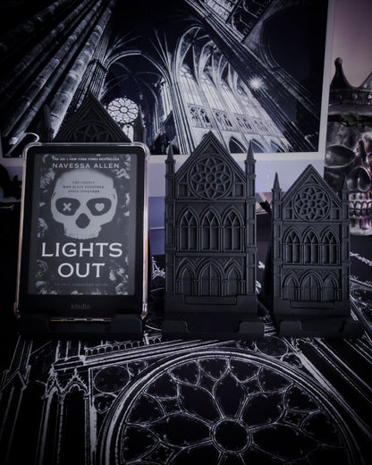 Black gothic cathedral device stands holding an e-reader on a table with cathedral interior imagery in the background