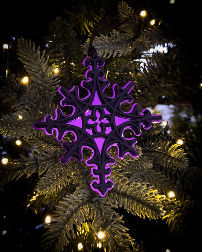 Purple gothic cathedral star ornament hanging on Christmas tree with warm lights