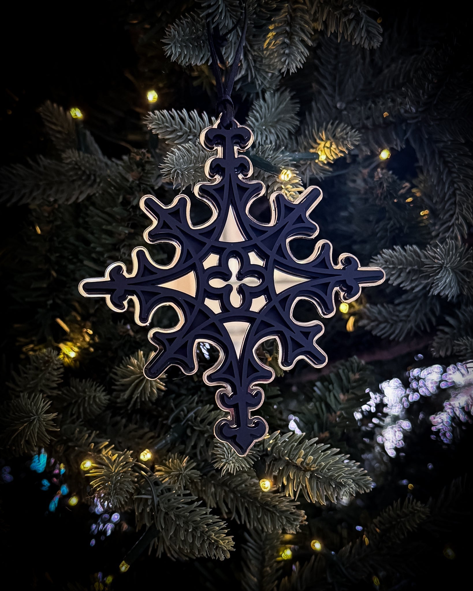 Gold Gothic cathedral star ornament hanging on Christmas tree with warm lights