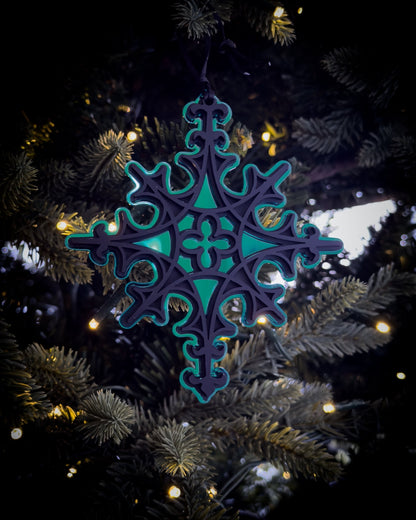 Green gothic cathedral star ornament hanging on Christmas tree with warm lights