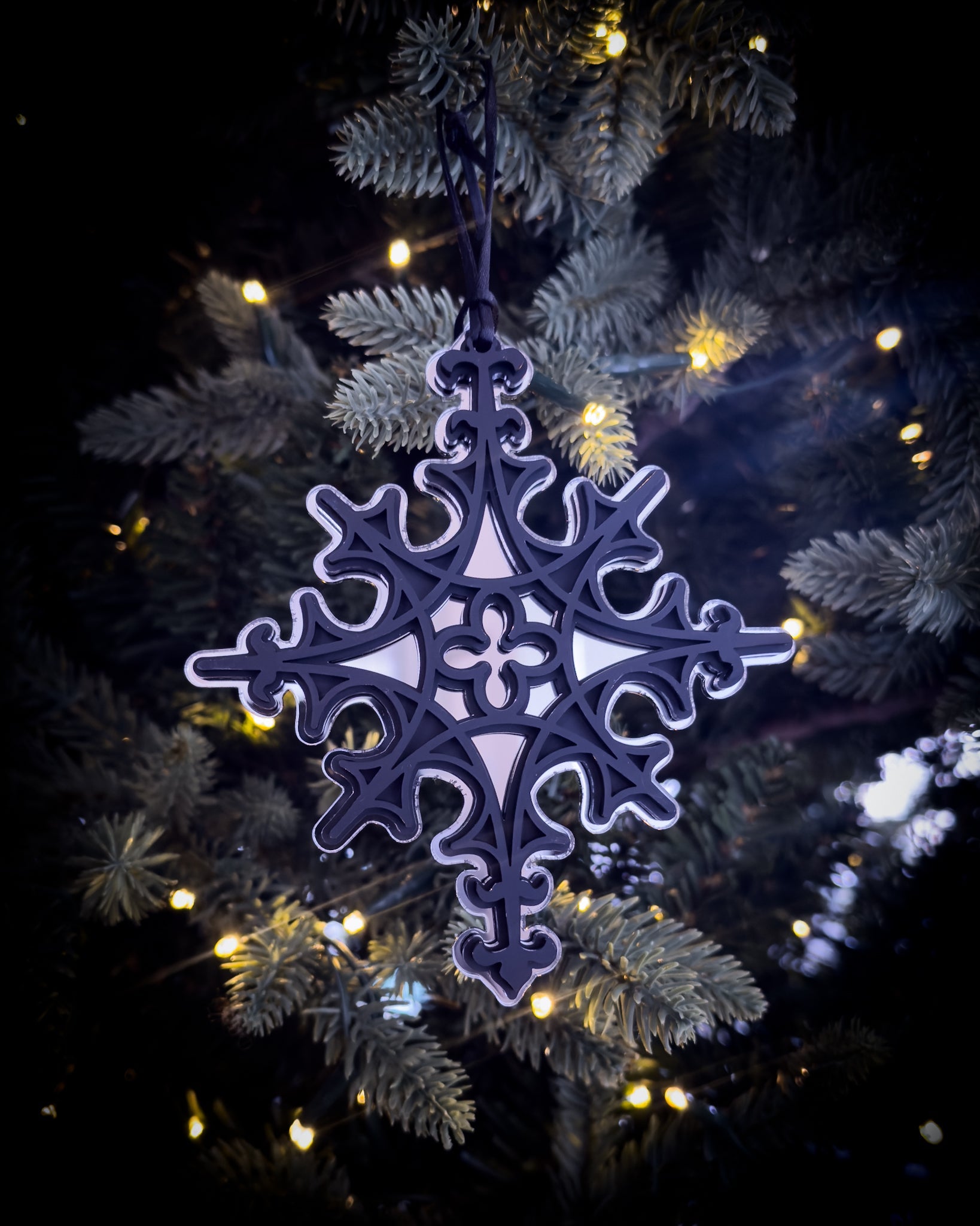 Silver gothic cathedral star ornament hanging on Christmas tree with warm lights