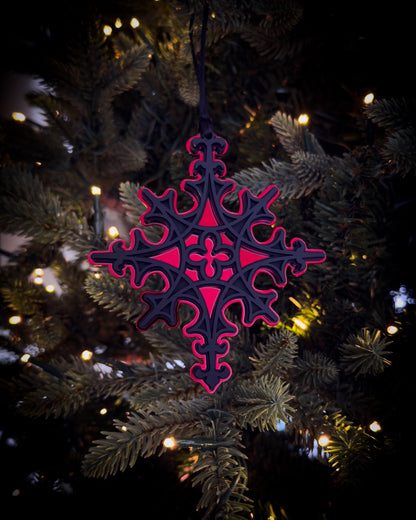 Red gothic cathedral star ornament hanging on Christmas tree with warm lights