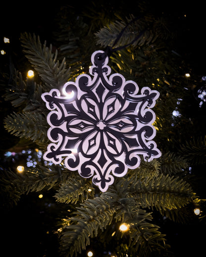 Silver gothic cathedral snowflake ornament hanging on Christmas tree with warm lights