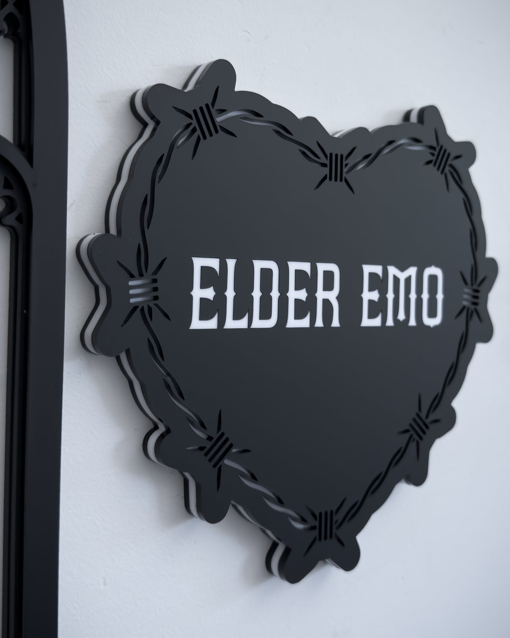 Side view of gothic barbed wire heart wall art with “Elder Emo” text