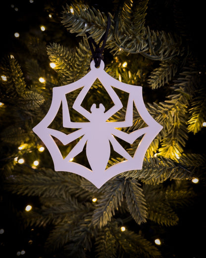 White acrylic, gothic spider web ornament hanging on Christmas tree with warm lights