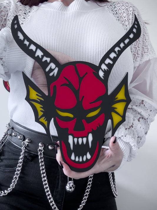 Red and black hellfire demon acrylic wall art with horns and fangs held by person for size reference