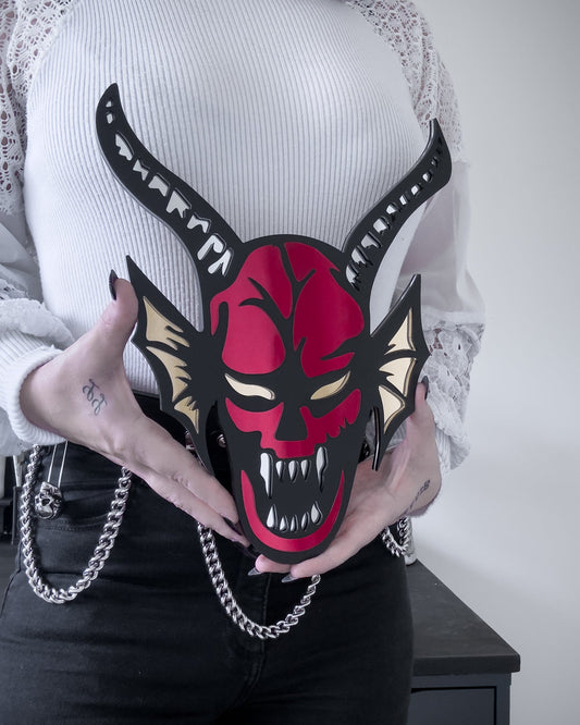 Red and black hellfire demon acrylic mirror wall art with horns and fangs held by person for size reference