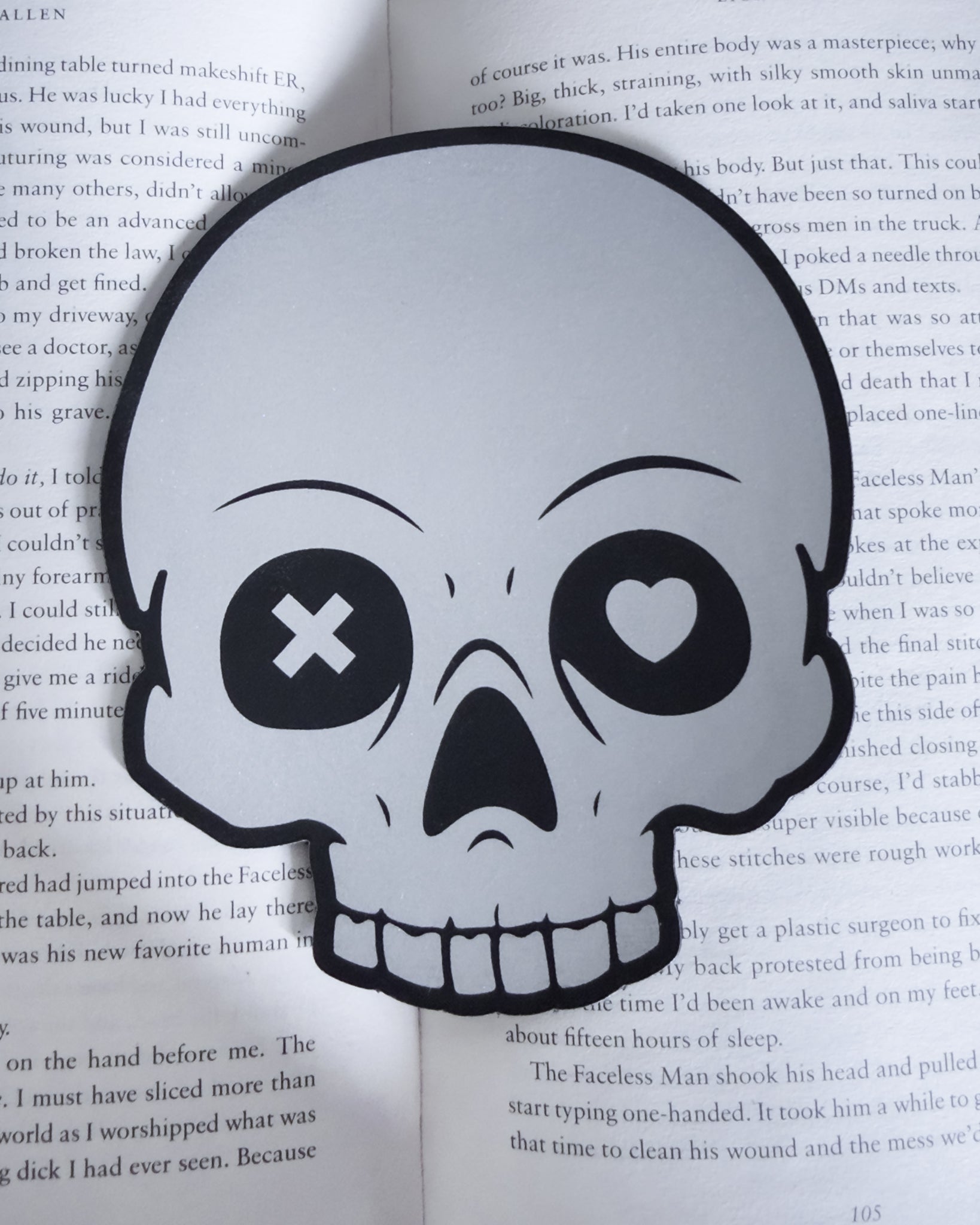 Gothic skull bookmark in black and silver leatherette, resting in a open book