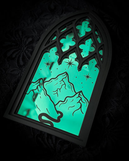 Gothic cathedral mirror wall art with teal acrylic window featuring engraved mountains and stars design on dark textured background