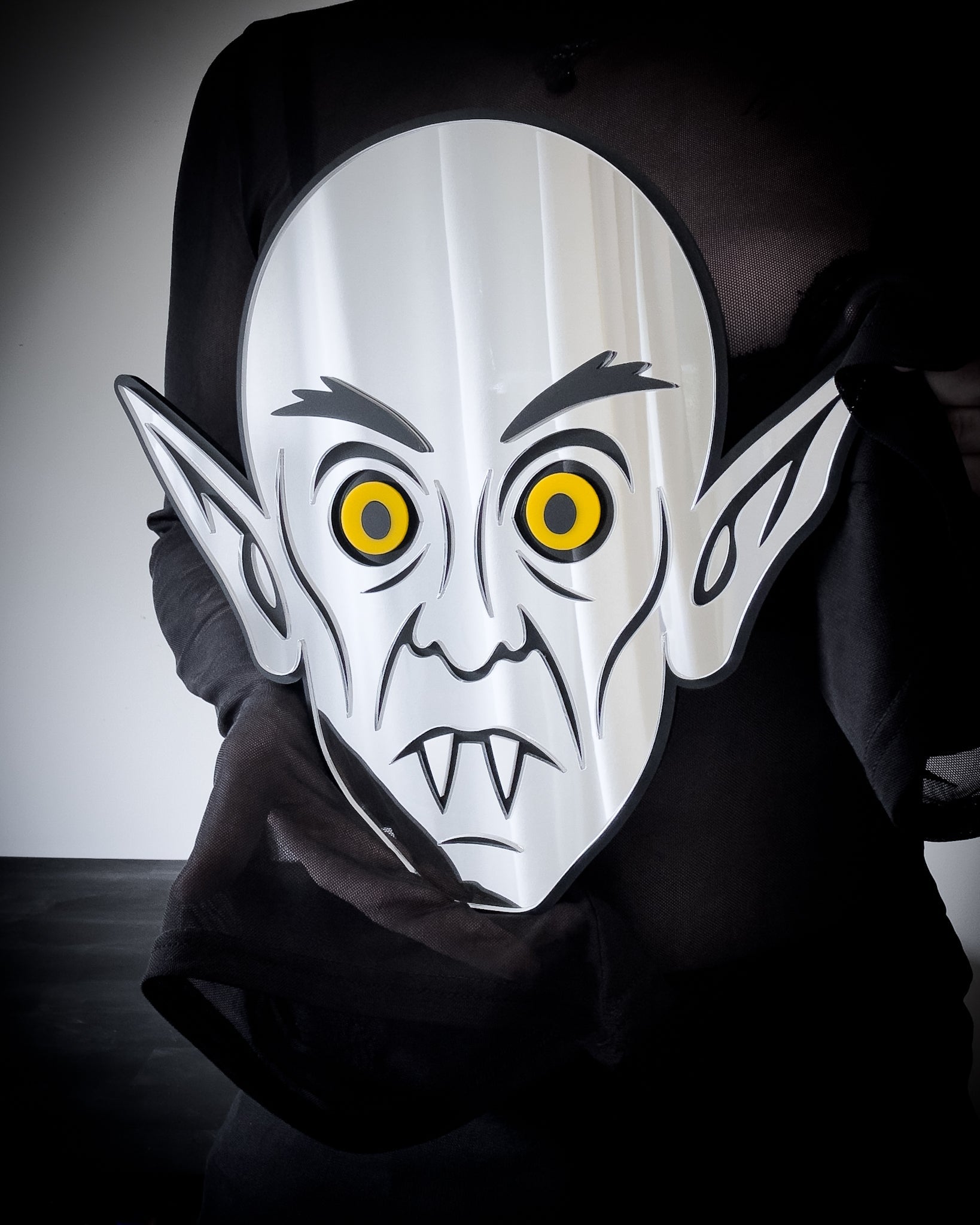 Gothic Mirror Nosferatu wall art with yellow eyes, held for scale
