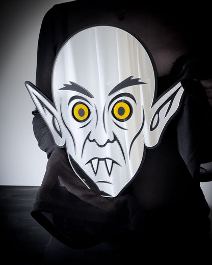 Gothic Mirror Nosferatu wall art with yellow eyes, held for scale