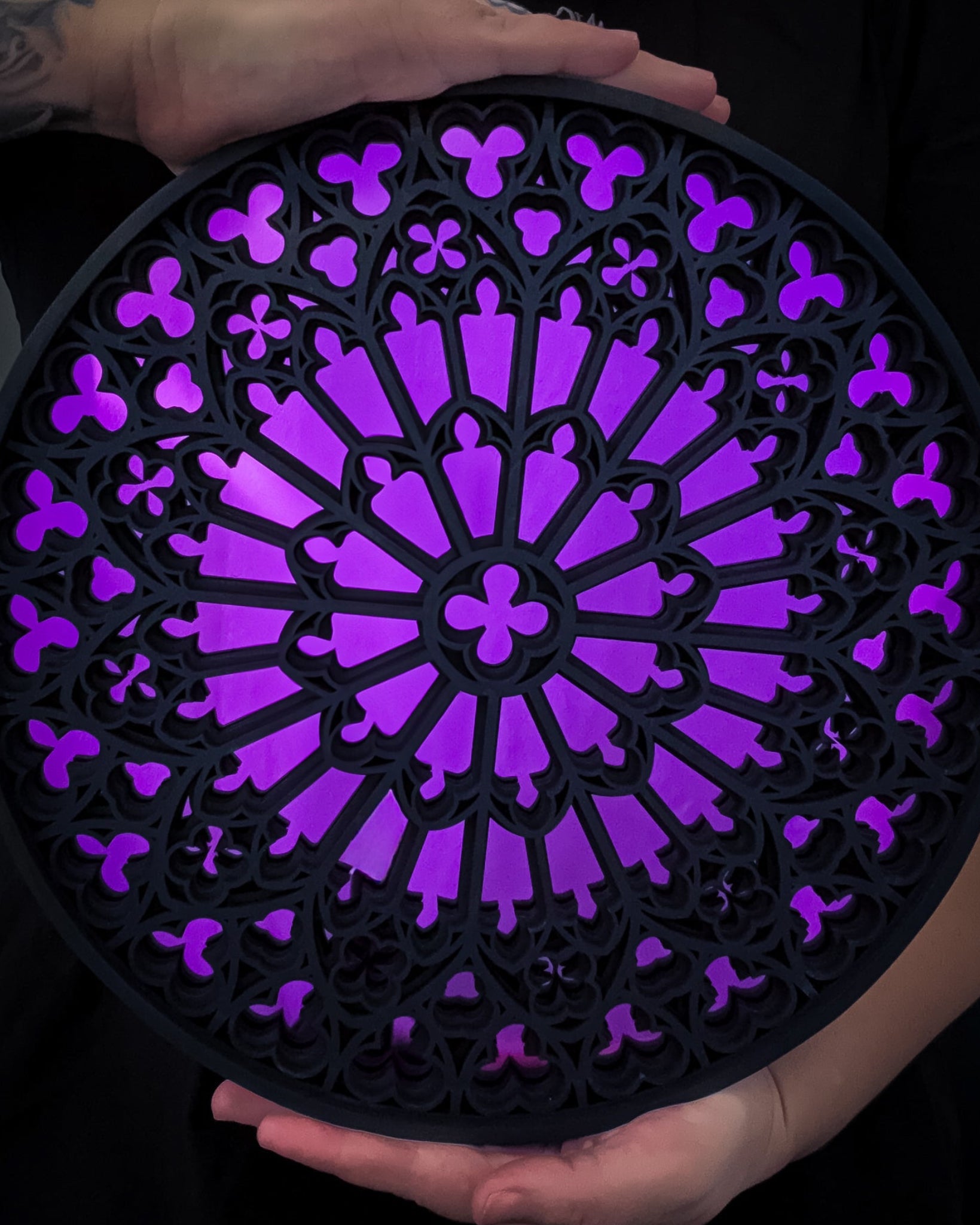 Notre Dame cathedral rose window mirror wall art in black stained wood with purple mirror centre held in hands for scale